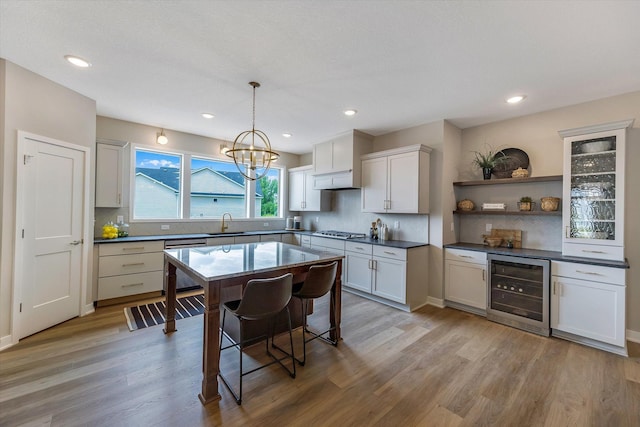 kitchen featuring wine cooler, stainless steel appliances, light wood-type flooring, open shelves, and a sink