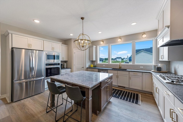 kitchen featuring light wood-type flooring, appliances with stainless steel finishes, decorative backsplash, and a sink