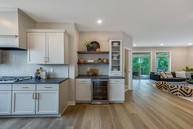 bar featuring stainless steel gas cooktop, tasteful backsplash, recessed lighting, light wood-type flooring, and beverage cooler