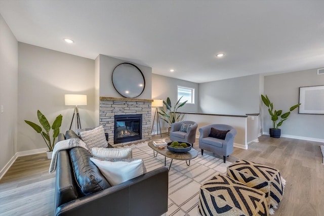 living room with light wood-type flooring, recessed lighting, baseboards, and a stone fireplace