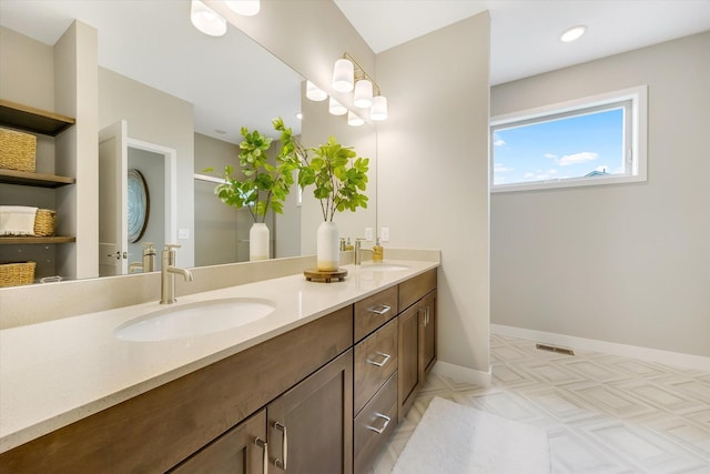 bathroom with a sink, a shower stall, baseboards, and double vanity