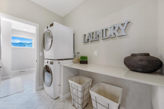 clothes washing area featuring laundry area, baseboards, and stacked washer / drying machine