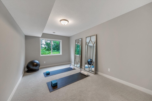 workout room with carpet, baseboards, and a textured ceiling