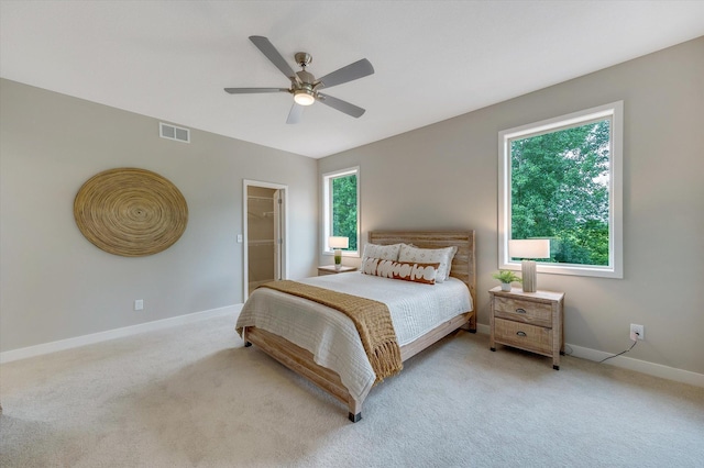 carpeted bedroom featuring ceiling fan, a spacious closet, visible vents, and baseboards