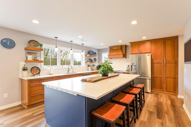 kitchen featuring brown cabinetry, premium range hood, appliances with stainless steel finishes, and open shelves