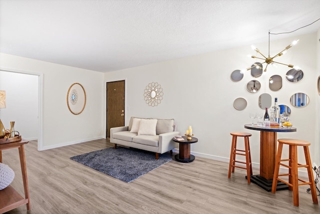 living room with baseboards, wood finished floors, and a notable chandelier