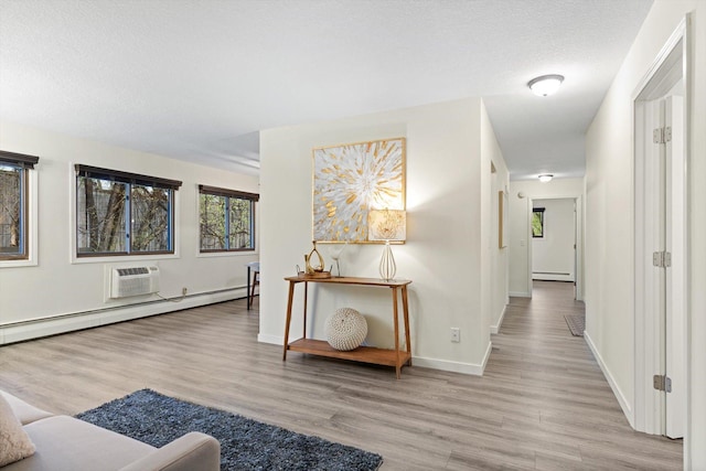 hallway featuring light wood-style floors, baseboards, baseboard heating, and a wall mounted AC