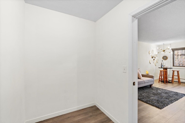 hallway featuring a textured ceiling, baseboards, and wood finished floors