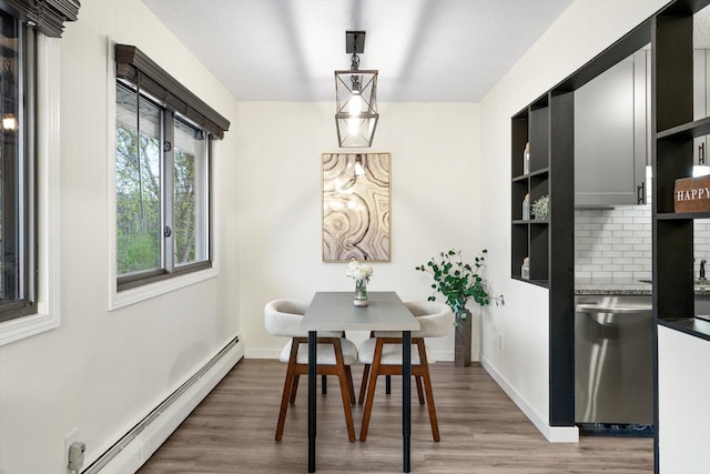 dining room with baseboards, baseboard heating, and wood finished floors