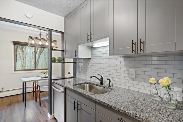 kitchen with stone countertops, a sink, dishwasher, and gray cabinetry