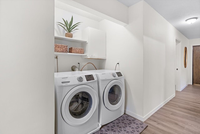 laundry area with separate washer and dryer, laundry area, light wood-style flooring, and baseboards