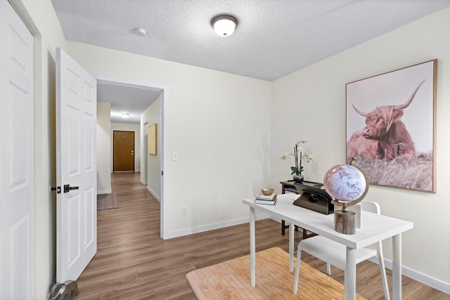 office with baseboards, a textured ceiling, and wood finished floors