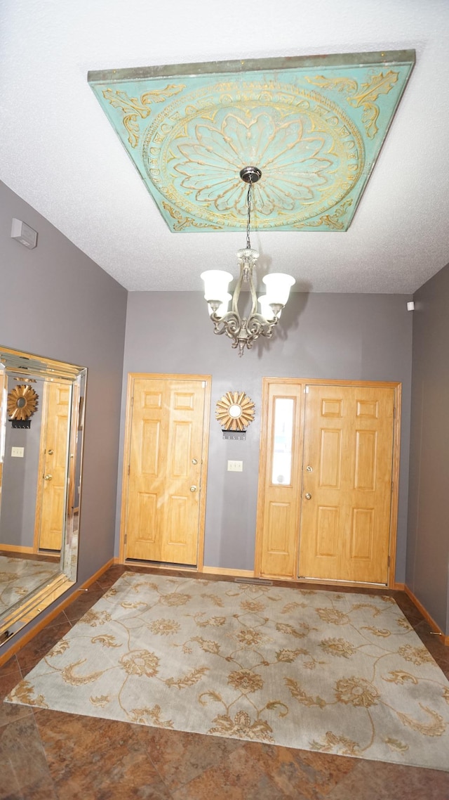 foyer entrance featuring an inviting chandelier, tile patterned flooring, baseboards, and a textured ceiling