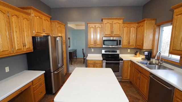 kitchen with a textured ceiling, light countertops, appliances with stainless steel finishes, and a sink