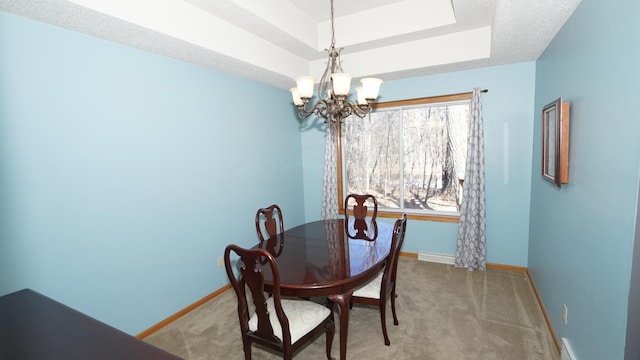 carpeted dining room featuring a notable chandelier, a raised ceiling, and baseboards