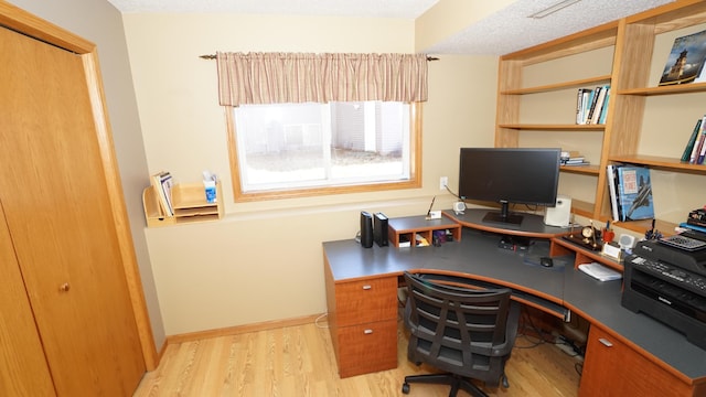 office space with a textured ceiling, light wood-type flooring, and baseboards