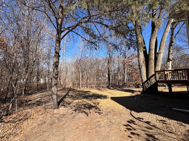 view of yard featuring a view of trees and a wooden deck