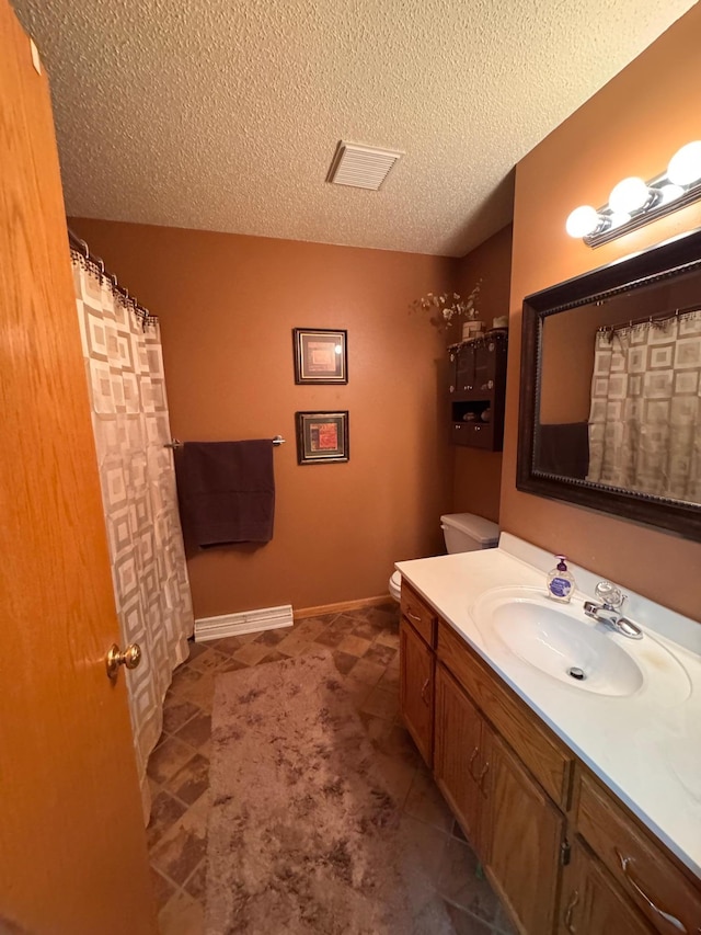 bathroom with visible vents, toilet, vanity, and a textured ceiling