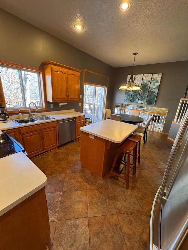 kitchen featuring light countertops, stainless steel dishwasher, a sink, and a wealth of natural light