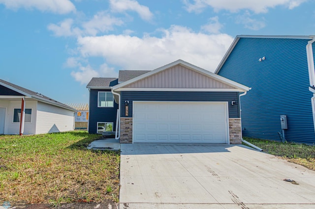 view of front facade featuring board and batten siding, a front yard, a garage, stone siding, and driveway