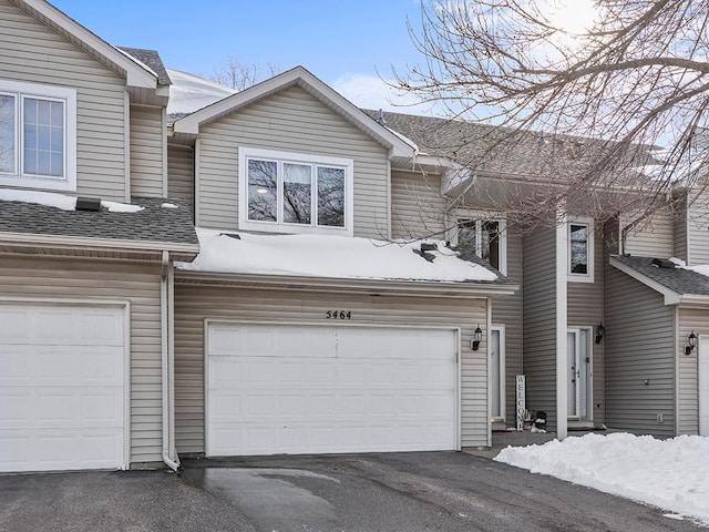 multi unit property with aphalt driveway, an attached garage, and a shingled roof