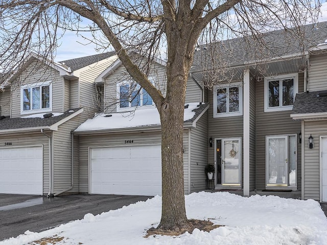 view of property featuring a garage, driveway, and a shingled roof