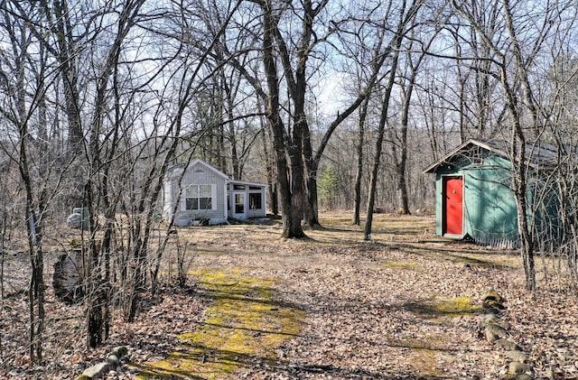 view of yard with an outdoor structure and a view of trees