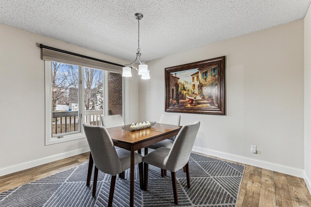 dining space featuring wood finished floors, baseboards, and a textured ceiling