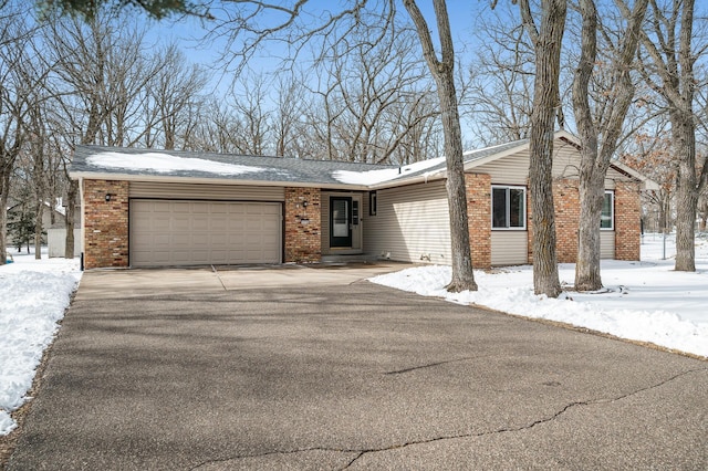 view of front facade with aphalt driveway, an attached garage, and brick siding