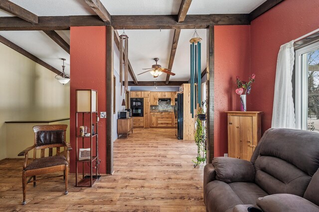 sitting room featuring ceiling fan, lofted ceiling with beams, and light wood finished floors