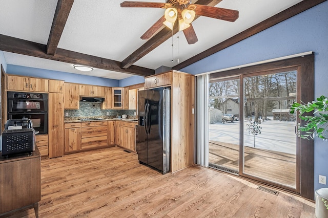 kitchen with light wood-style flooring, backsplash, under cabinet range hood, and black appliances