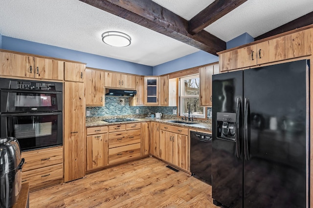 kitchen featuring a sink, under cabinet range hood, light wood-type flooring, black appliances, and beam ceiling