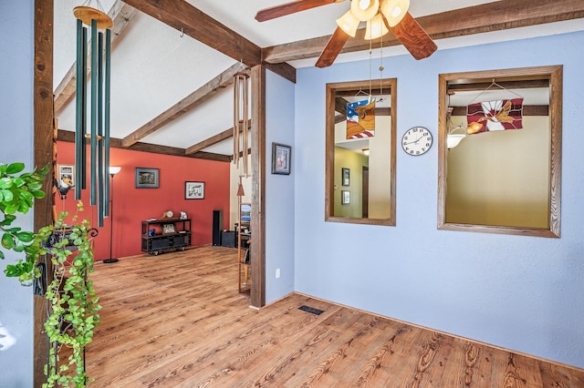 unfurnished room featuring ceiling fan, visible vents, vaulted ceiling with beams, and wood finished floors