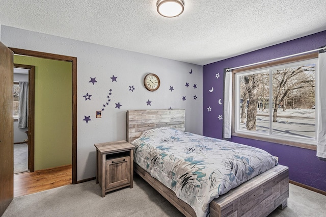 bedroom featuring baseboards, a textured ceiling, and light colored carpet