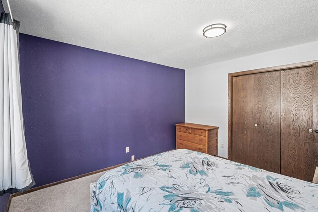 bedroom with carpet, a closet, a textured ceiling, and baseboards