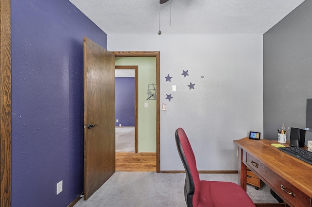 carpeted office space with a textured ceiling and baseboards