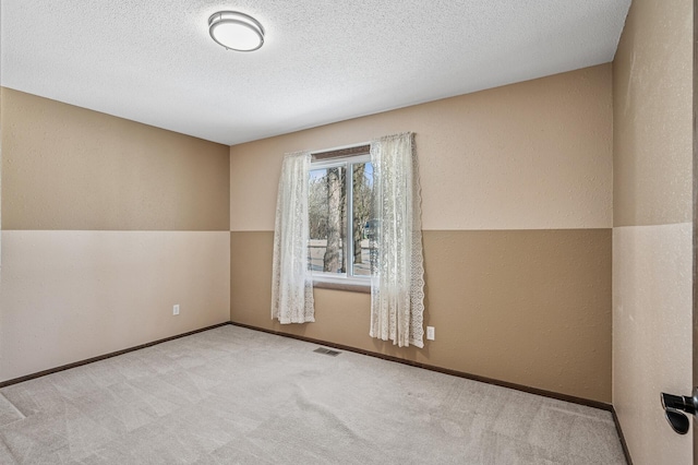 unfurnished room with visible vents, a textured wall, carpet flooring, a textured ceiling, and baseboards