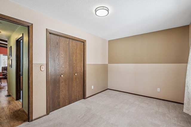 unfurnished bedroom featuring baseboards, visible vents, carpet, a textured ceiling, and a closet