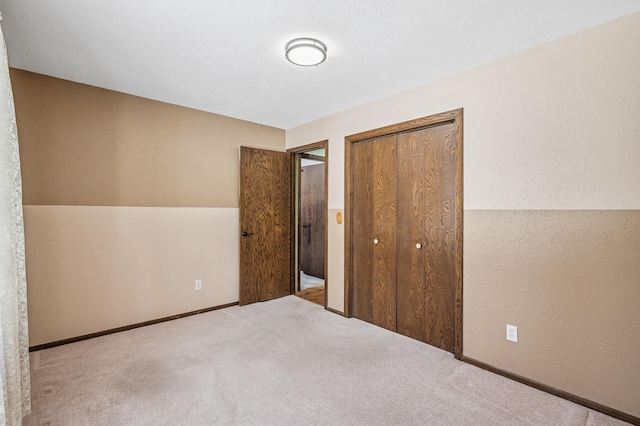 unfurnished bedroom featuring carpet, baseboards, and a closet