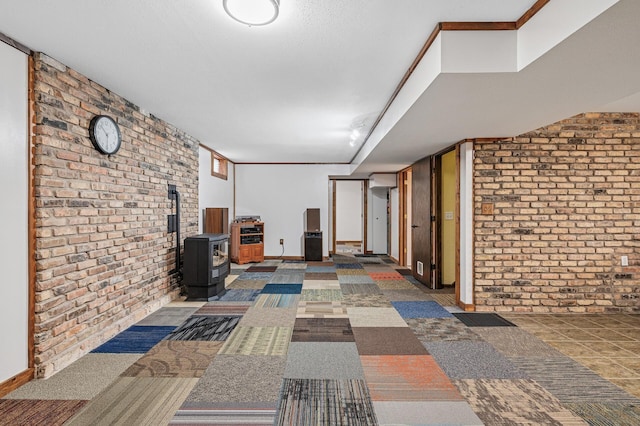 interior space featuring brick wall, ornamental molding, and baseboards