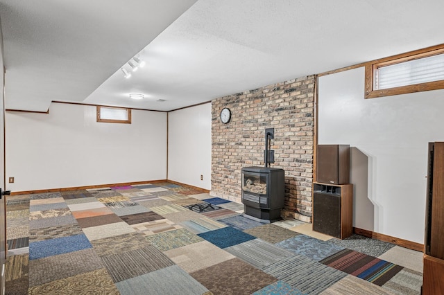 below grade area with carpet, a wood stove, a textured ceiling, and baseboards