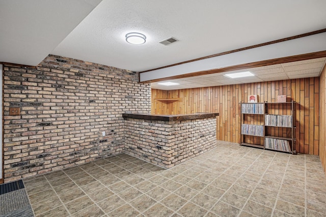 bar featuring a bar, brick wall, wooden walls, and visible vents