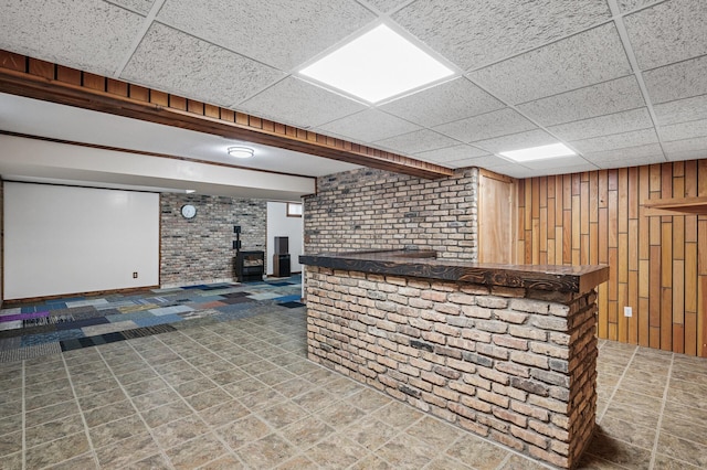 bar with a paneled ceiling, wooden walls, brick wall, a dry bar, and a wood stove