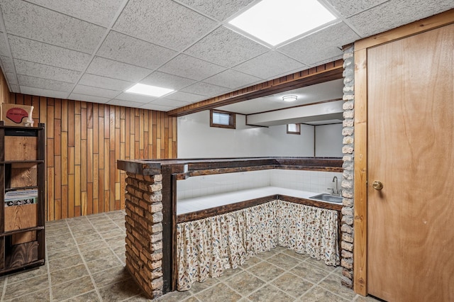 bar featuring a drop ceiling, a sink, and wooden walls