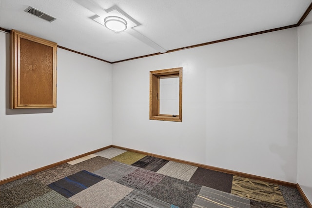 carpeted spare room featuring visible vents, crown molding, and baseboards