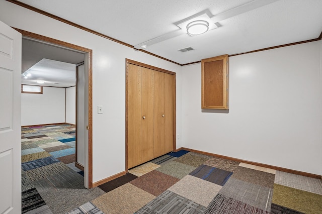 bedroom with baseboards, ornamental molding, carpet, a textured ceiling, and a closet