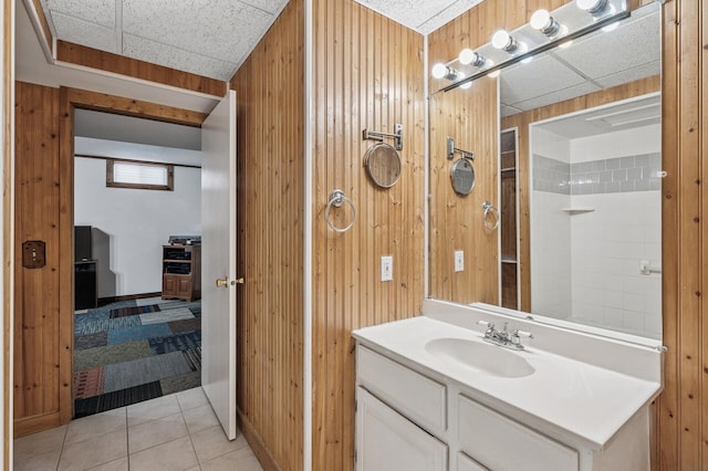 bathroom featuring wood walls, a drop ceiling, tile patterned flooring, and vanity