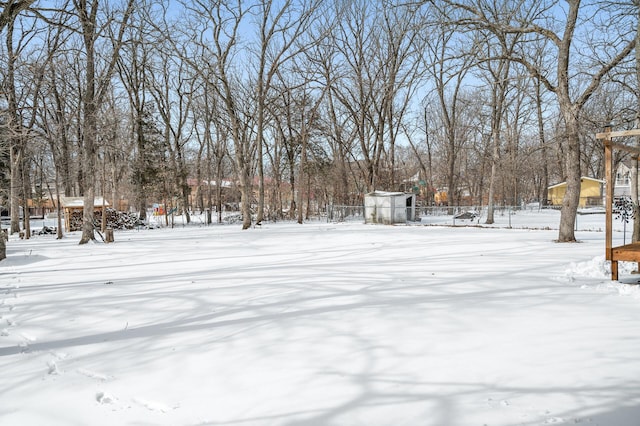 yard layered in snow featuring an outbuilding, fence, and a shed