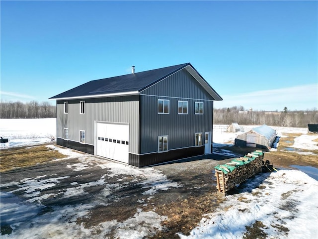 snow covered property with a detached garage and an outdoor structure