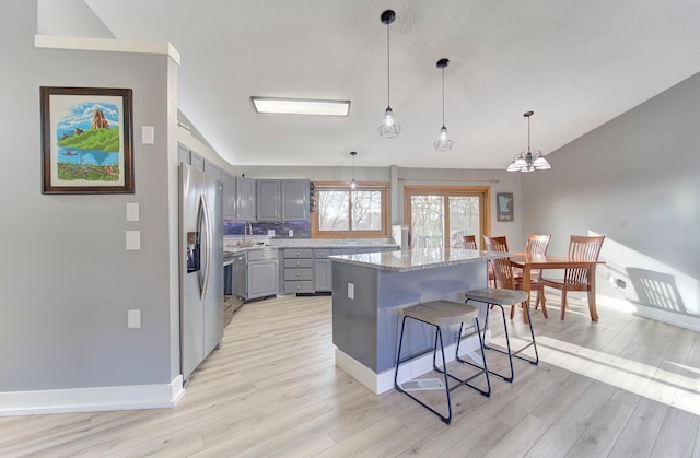 kitchen featuring light wood-style flooring, a sink, vaulted ceiling, gray cabinets, and stainless steel fridge with ice dispenser